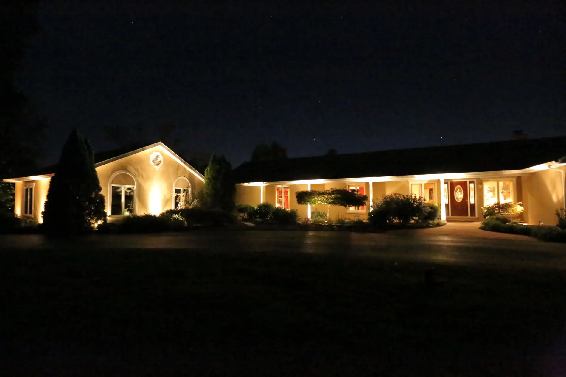 Ranch home with full low-voltage facade and landscape lighting at night
